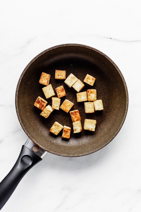 tofu cut into cubes in a frying pan