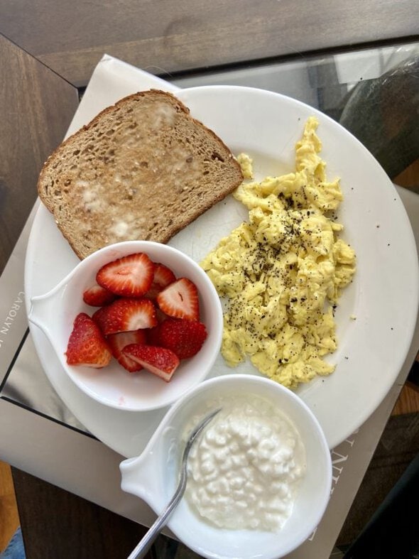 breakfast plate with eggs, toast, berries, and cottage cheese.